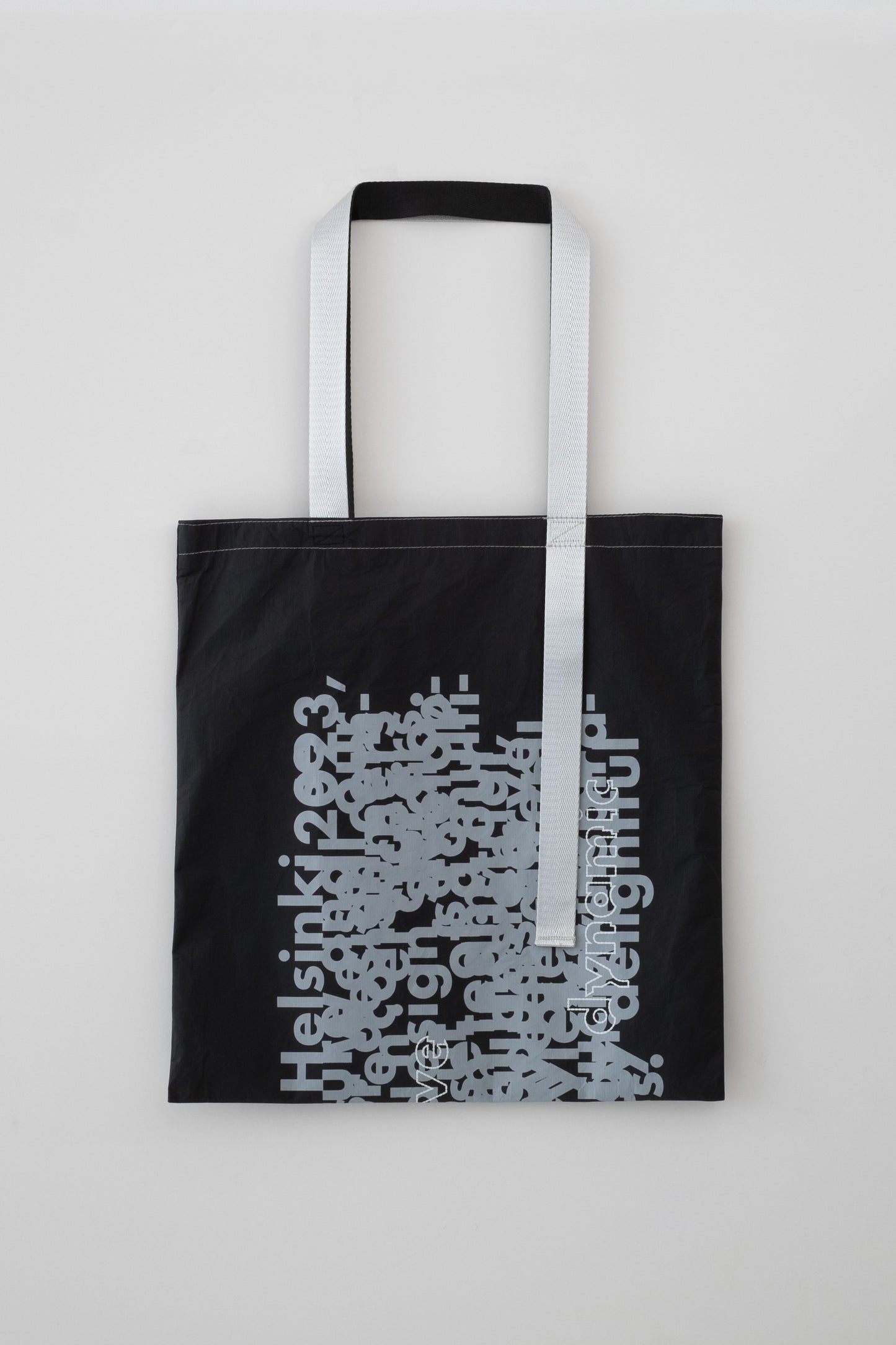 Flat-lay back view of the D-ja Tote Bag, highlighting its contrasting asymmetrical black and silver handles, and bold yet minimalist aesthetic.