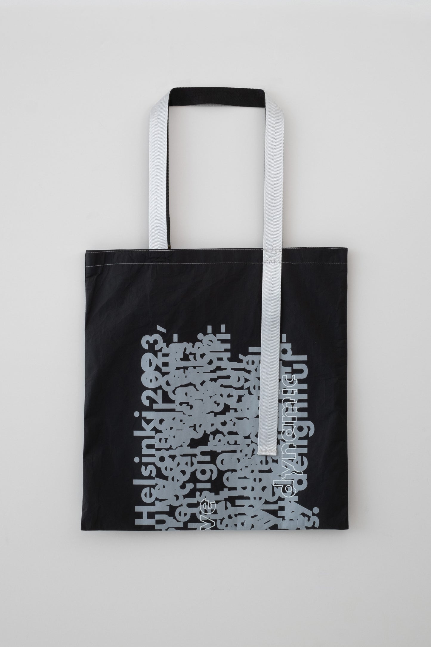 Flat-lay back view of the D-ja Tote Bag, highlighting its contrasting asymmetrical black and silver handles, and bold yet minimalist aesthetic.