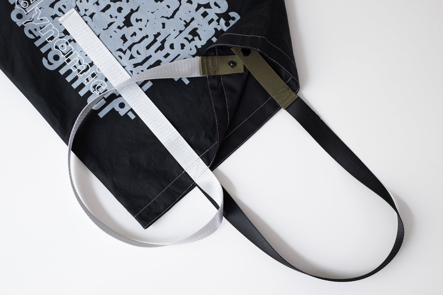 Close-up of the D-ja Tote Bag Plus extra strap in moss, featuring a buttoned closure for added functionality while maintaining its signature lightweight design.