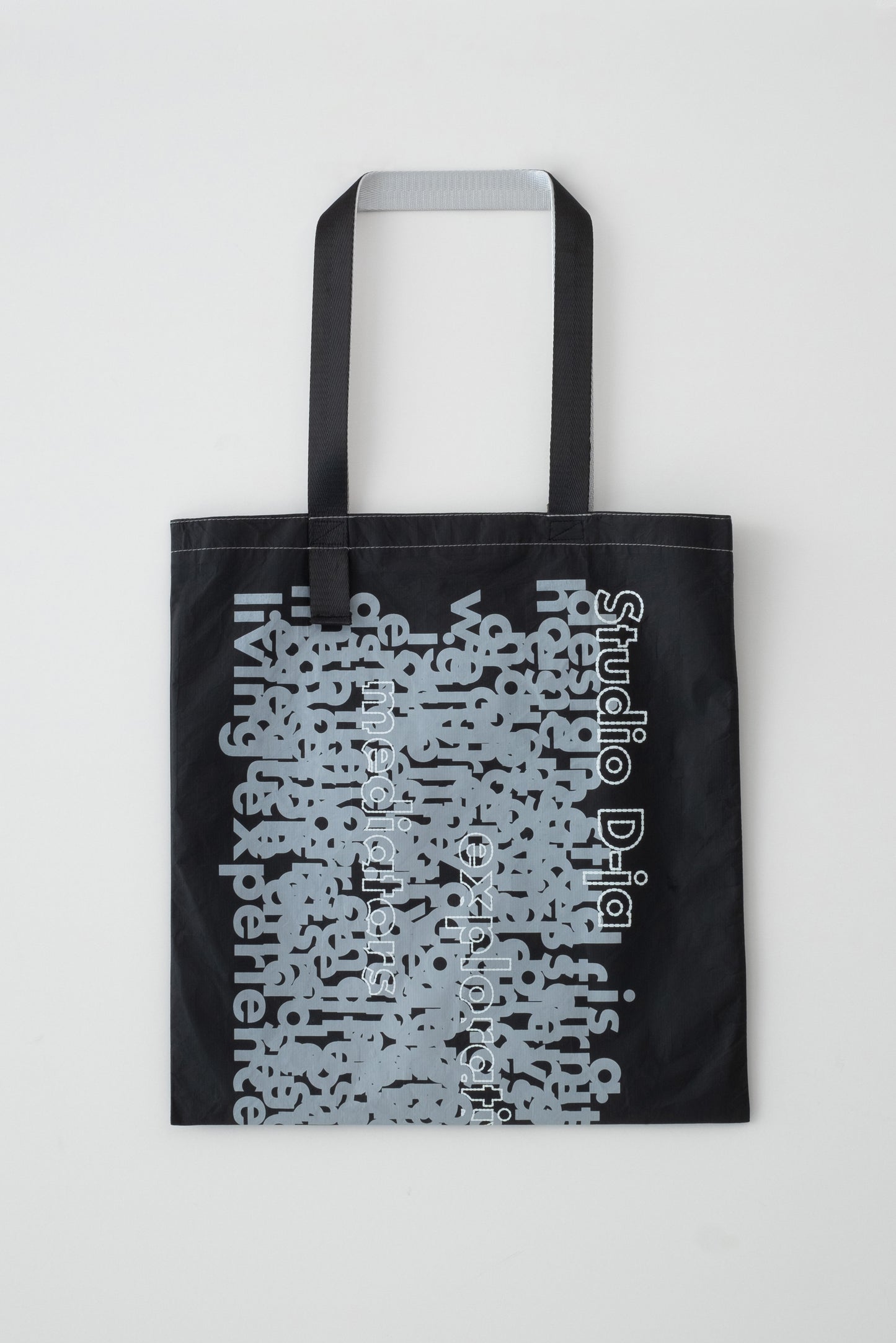 Flat-lay front view of the D-ja Tote Bag, featuring bold, expressive typography on lightweight, durable Tyvek®, designed for modern city life.