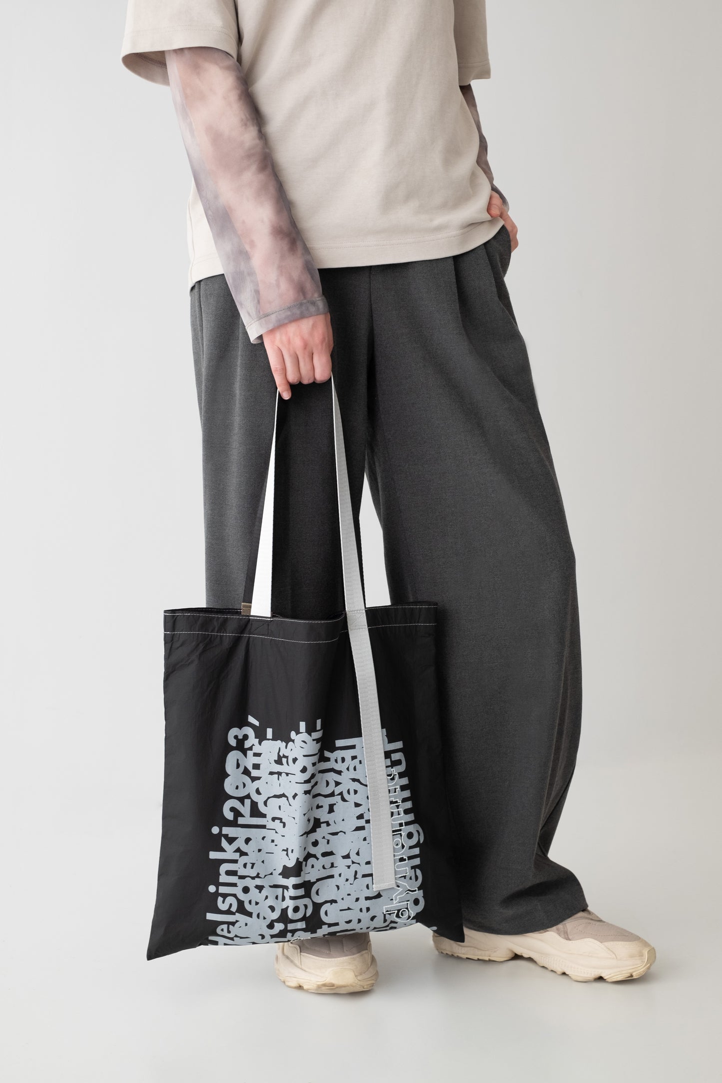 The D-ja Tote Bag being carried, featuring bold graphic prints and contrasting handles in black and silver, adding a playful and modern touch to urban lifestyles.