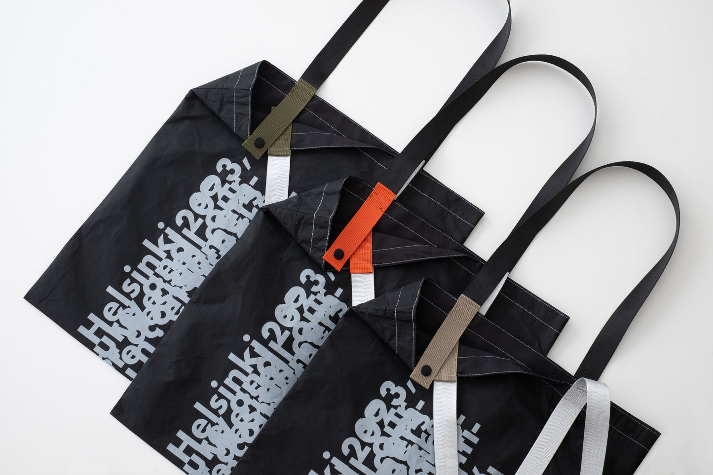 Three D-ja Tote Bag Plus in moss, persimmon, and sand colour options, highlighting the inner strap colours that add a playful and personal touch.