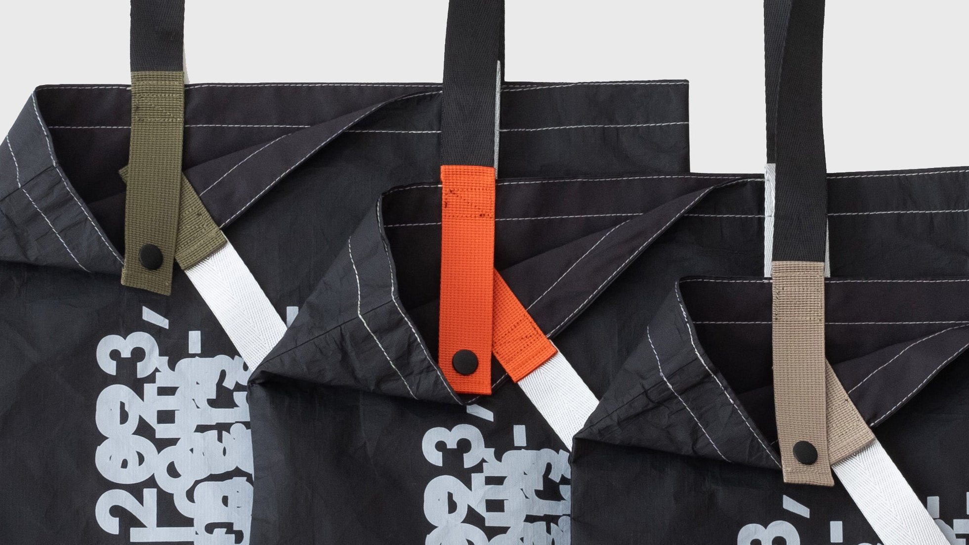 Three D-ja Tote Bag Plus in moss, persimmon, and sand colour options, highlighting the inner strap colours that add a playful and personal touch.