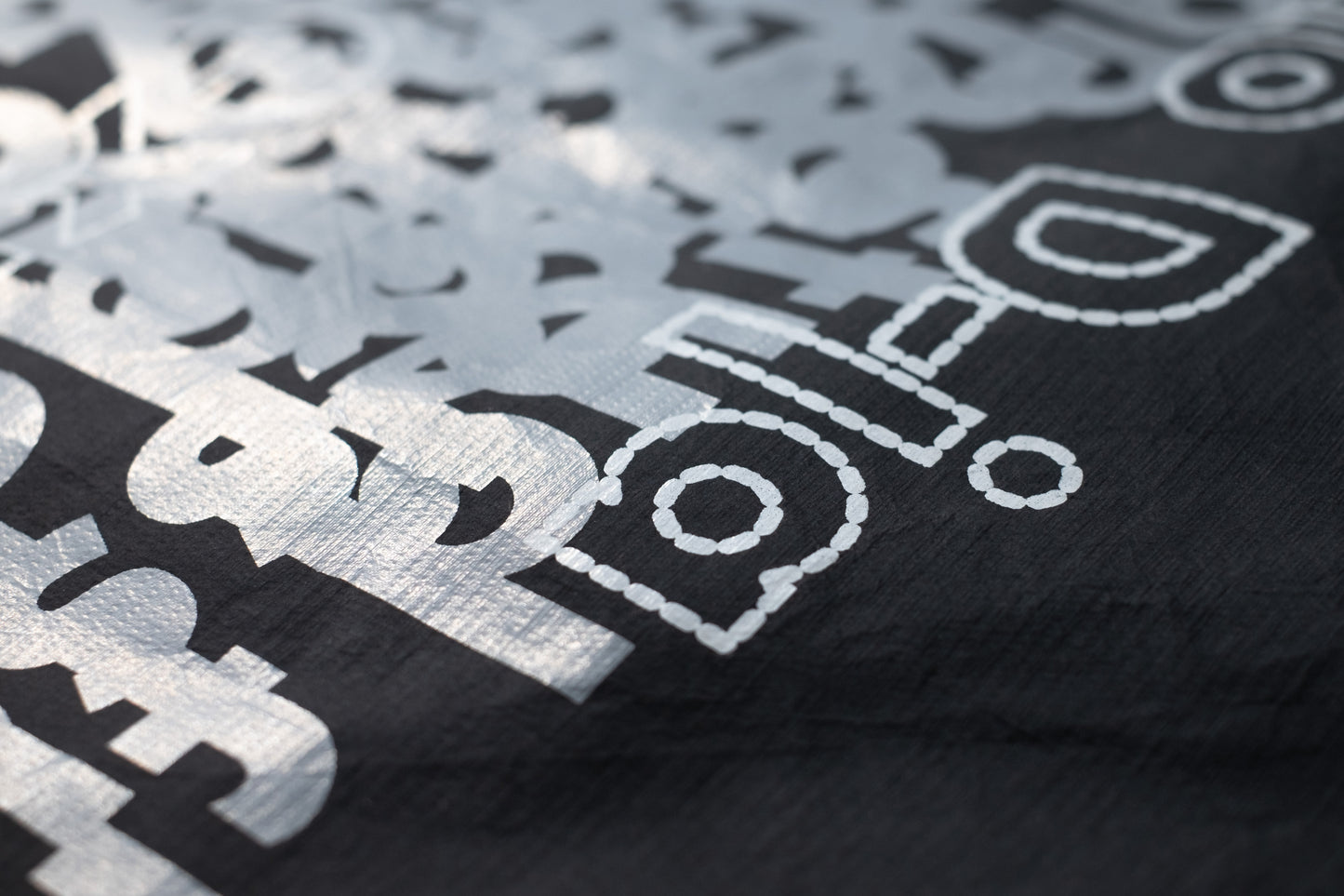 Close-up of the D-ja Tote Bag’s soft, paper-like Tyvek® material, highlighting its unique texture and layered text print, inspired by experimental design.