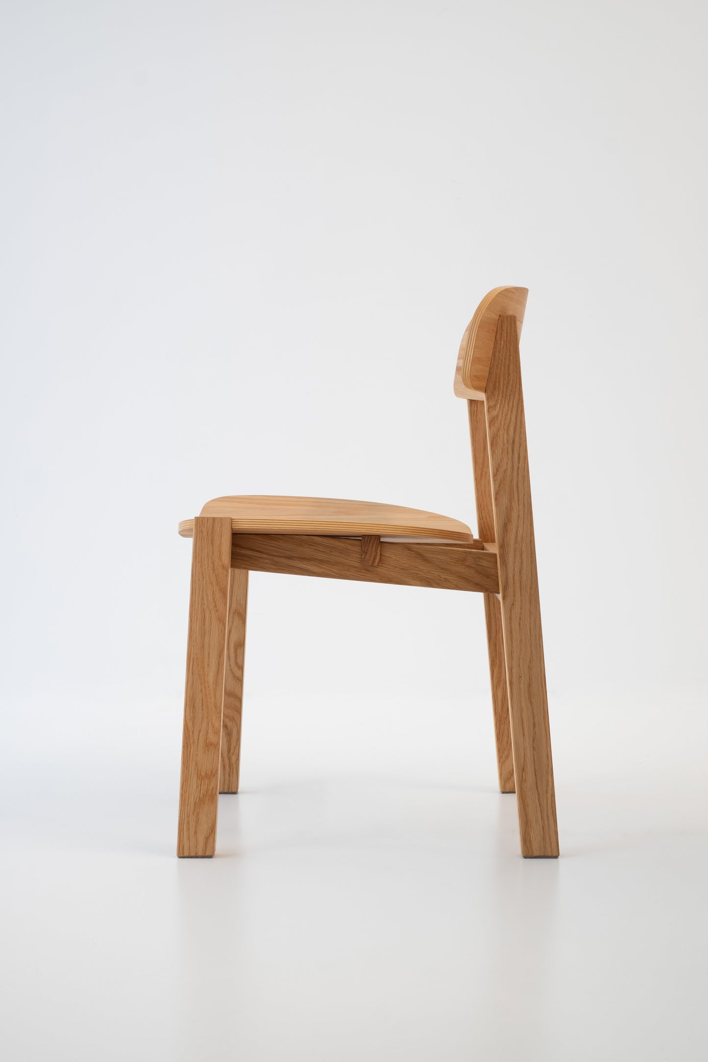 Siirto Chair from the left side view, highlighting the elegant craftsmanship and solid wood frame.