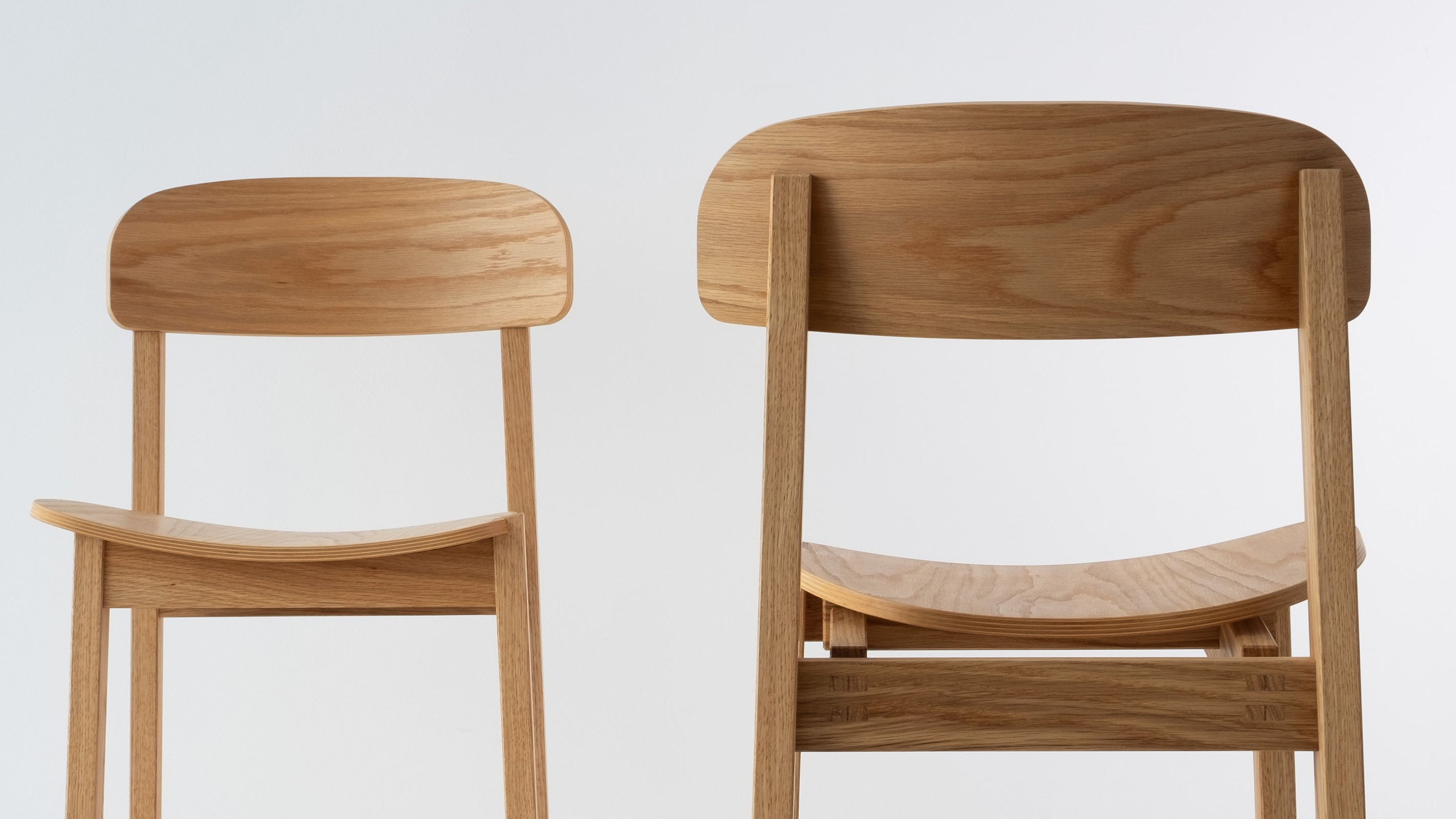 Siirto Chairs from the front and back view, highlighting the contrasting asymmetrical design of the backrest and seat when viewed from both angles.