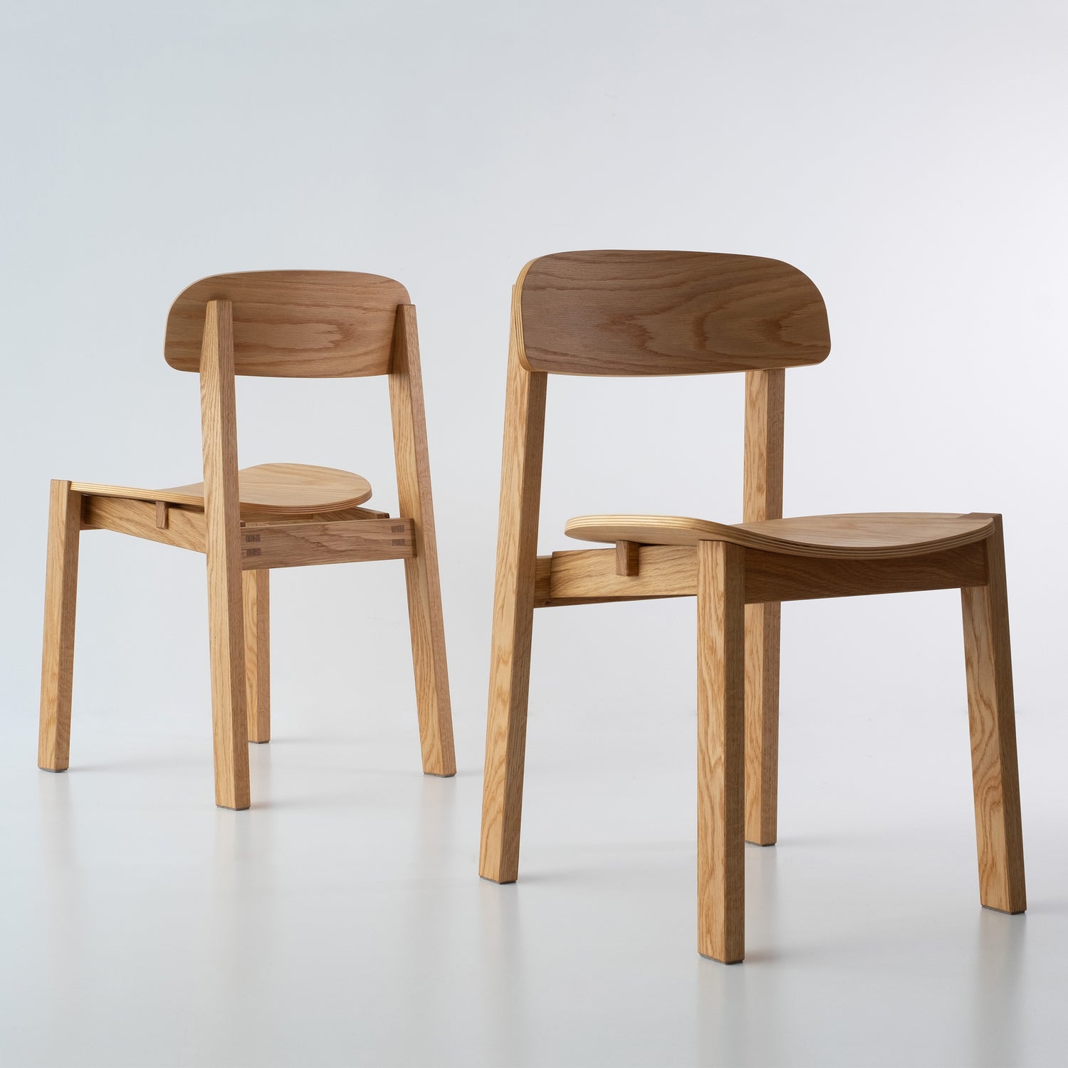 Siirto Chairs from the front and back view, highlighting the contrasting asymmetrical design of the backrest and seat when viewed from both angles.