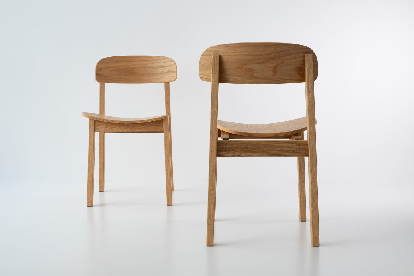 Siirto Chairs from the front and back view, highlighting the contrasting asymmetrical design of the backrest and seat when viewed from both angles.